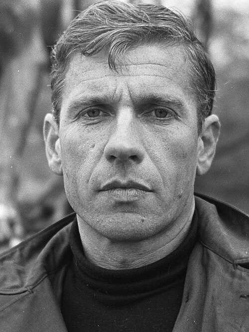 A black and white photo of a handsome, middle aged white man with prominent features, a lined forehead, and a serious expression.